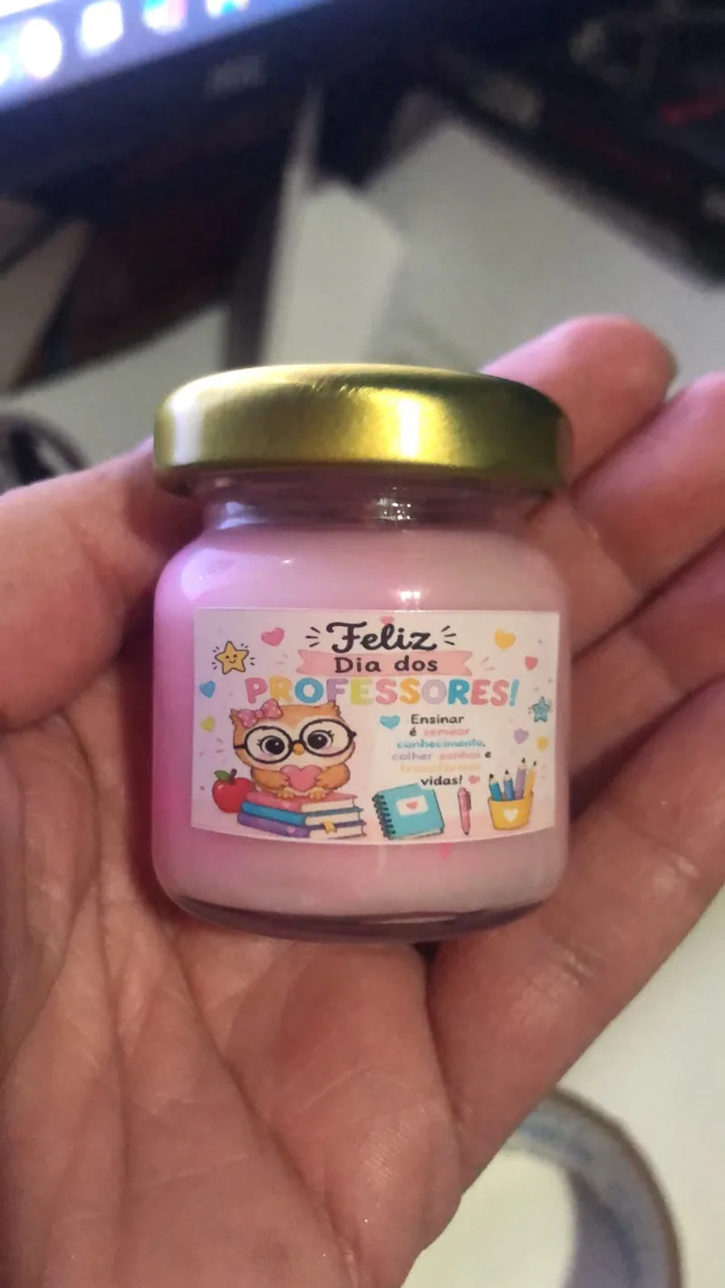 Vela rosa com tampa dourada e rótulo de Feliz Dia dos Professores