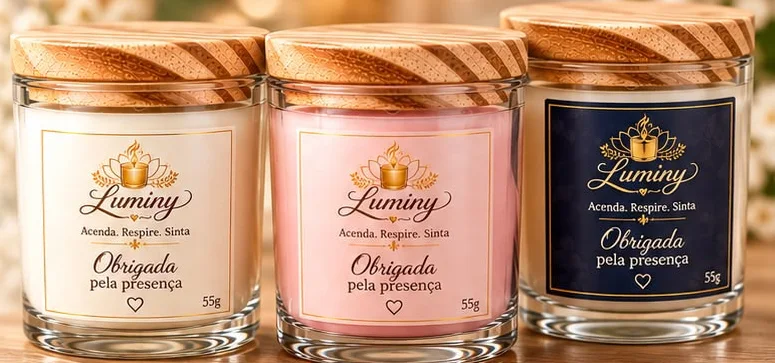 Três velas Luminy com rótulos diferentes: creme, rosa e azul-marinho